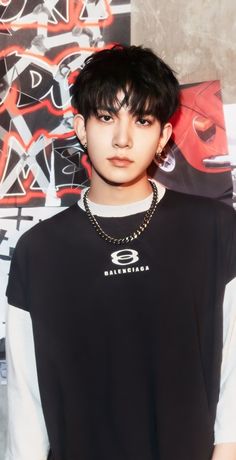 a young man wearing a black shirt standing in front of graffiti