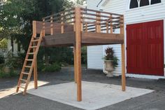 a wooden bunk bed next to a red door and white house with potted plants