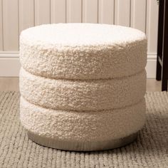 a white round ottoman sitting on top of a rug