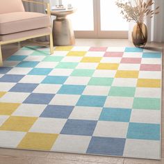 an area rug with multicolored squares on it in front of a chair and window