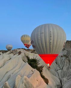 three hot air balloons flying over some rocks