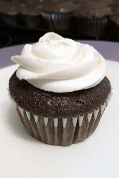 a chocolate cupcake with white frosting on a plate