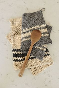 a wooden spoon sitting on top of two knitted napkins next to each other