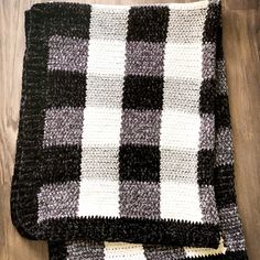 a black and white checkered blanket laying on top of a wooden floor next to a pair of scissors