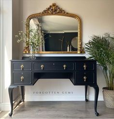 a black and gold desk with a mirror on it next to a potted plant