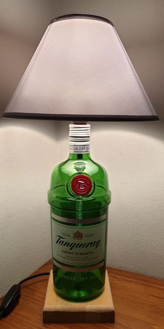 Beautiful abat-jour made with Tanqueray gin bottle on natural beech wood support. The lampshade is in gray fabric, the E27 lamp holder is wired with switch. The plug is Italian 10A. Decorate your room, living room or office desk with this original lamp that will give a touch of uniqueness to your environment! Wide availability of bottles! Ask if there is your favorite and I will make it just for you! If you like the item but prefer a different size or color or you have something special in mind, Jager Bottle Lamp, Gin Tanqueray, Tanqueray Gin, Liquor Bar, Gin Bottle, Bar Man Cave, Gin Bottles, Bottle Lamp, Bottle Lights