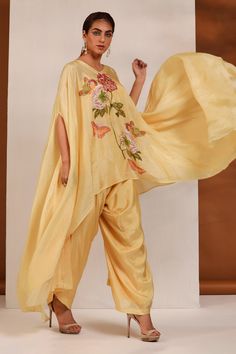 Yellow cape tunic with floral print and asymmetric hem. Paired with dhoti pant.
Component: 2
Pattern: Printed
Type Of Work: Floral
Neckline: V neck
Sleeve Type: Flared sleeves
Fabric: Bemberg Silk, Lining: Cambric
Color: Yellow
Other Details: 
Asymmetric cape tunic
Occasion: Sangeet - Aza Fashions Bohemian Raw Silk Sets With Traditional Drape, Traditional Saree Pant Set With Pallu, Traditional Pant Set With Sheer Dupatta And Traditional Drape, Traditional Pant Set With Sheer Dupatta And Drape, Traditional Semi-stitched Pant Set With Sheer Dupatta, Bohemian Cotton Silk Set With Sheer Dupatta, Traditional Pant Set With Dabka And Traditional Drape, Bohemian Set With Sheer Dupatta In Cotton Silk, Traditional Dabka Pant Set For Summer