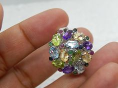 About Item: METAL: Sterling silver with a rhodium coating. 925 MARK: Yes STONE: Amethyst, Yellow Topaz, Peridot, Emerald, Ruby, Blue Sapphire & Aquamarine. (All are natural stones) Number of Amethyst: 3 pcs (4X6mm) Number of Ruby's: 4 pcs (2mm Round) Number of Topaz: 3 Pcs (4X6mm) Number of Peridot: 3 Pieces (4x6mm) Number of emeralds: 5 pcs (2mm Round) Number of Sapphire: 4 pcs (2mm Round) Number of Aquamarine: 3 pcs (4x6mm) Designed By Talisman SHIPPING & HANDLING: We ship through USPS within Silver Amethyst Multi-stone Ring, Multicolor Multi-stone Amethyst Ring In Sterling Silver, Multicolor Amethyst Ring In Sterling Silver For Anniversary, Multicolor Amethyst Sterling Silver Ring For Anniversary, Silver Oval Multi-stone Gemstones, Oval Silver Multi-stone Gemstones, Oval Multi-stone Silver Gemstones, Fine Jewelry Multi-stone Silver Gemstones, Silver Cluster Jewelry With Gemstone Accents