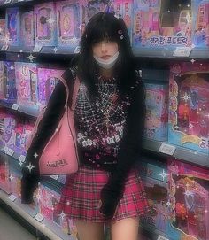 a woman in a pink skirt and black sweater is standing next to a shelf full of barbie dolls