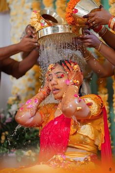 a woman is getting her face covered with water from a bucket as she gets ready to dance