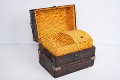 an old wooden box with yellow fabric in it