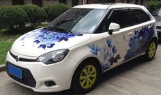 a small white car with blue flowers painted on it's side and yellow rims