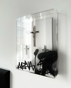 a mirror mounted to the side of a wall next to a black and white cross