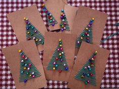 four christmas trees made out of brown paper on a checkered tablecloth with beads