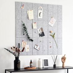 a black table topped with vases filled with flowers and plants next to a white wall