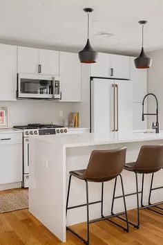 a kitchen with three stools next to an island in the middle of the room