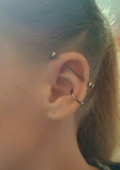 a close up of a person wearing an ear cuff with two piercings on their ears