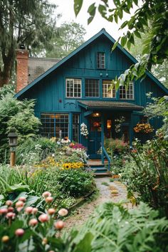 a blue house surrounded by lush green trees and flowers