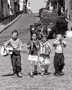 three children are walking down the street with their guitars in hand and one boy is holding a guitar