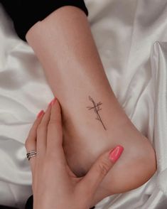 a woman's foot with a small cross tattoo on the side of her leg