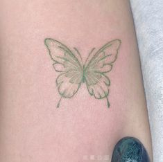 a small green butterfly tattoo on the back of a woman's arm and leg