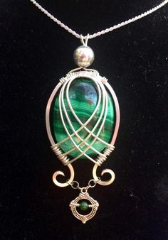 a green and silver necklace with an oval shaped pendant hanging from it's side