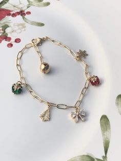 This 14K gold-plated large link chain charm bracelet is so festive, cute, and beautiful. It contains 6 different holiday charms including a bow with cubic zirconia, Christmas tree, snowflake, a red and green crystal gift box, and ends with a bell. It is perfect to wear the entire holiday season or a perfect gift for a friend, girlfriend/significant other, yourself, or anyone you choose.   Product Details:  Length:  - Total link chain 8.5 inches - Can fit wrist sizes between 5.75 inches to 7.5 in Gold Plated Dangle Charm Bracelet Gift, Gold Charm Bracelet With Lobster Clasp For Party, Gold Plated Charm Bracelet For Gift, Gold Bracelet With Dangling Charms As Gift, Gold Christmas Party Bracelets, Gold-tone Gold Plated Charm Bracelet Gift, Gold Plated Bracelets With Dangling Charms For Gift, Gold Dangle Jewelry For Christmas, Gold Christmas Festive Bracelets