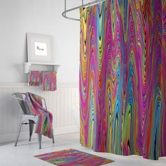 a colorful shower curtain in a white bathroom with a chair and rug on the floor