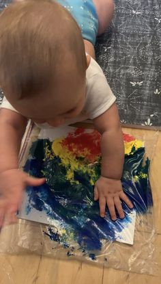 a baby is playing with some paint on the floor