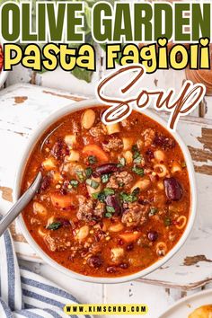 Bowl of pasta fagioli soup with ingredients and a spoon on a table.