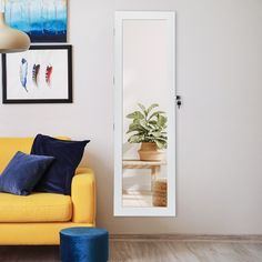 a living room with a yellow couch and blue throw pillows on the floor next to a white door