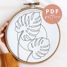 a person is holding up a hand embroidery pattern