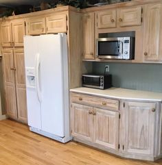 a white refrigerator freezer sitting inside of a kitchen next to wooden cupboards and drawers