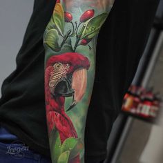 a man with a tattoo on his arm has a red parrot and leaves on it