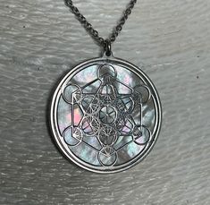 "Metatron in argento 925 e madreperla bianca naturale. Il cubo di Metatron prende il suo nome dall'Arcangelo omonimo, conosciuto anche come scriba di Dio. È costituito da un cubo che rappresenta la stessa matrice dell'universo e il punto di unione tra il maschile e il femminile. Nasce dall'incontro di tredici sfere che indicano l'energia femminile e nel tracciare il frutto della vita. Dal centro di ogni sfera si irradiano delle linee rette che simboleggiano invece l'energia maschile. Al centro a Engraved Silver Mother Of Pearl Necklace, Silver Medallion With Mother Of Pearl, Pendant Necklaces, Silver Fashion, Hippie Boho, Jewelry Necklace Pendant, Necklace Lengths, Etsy Accessories, Handmade Items