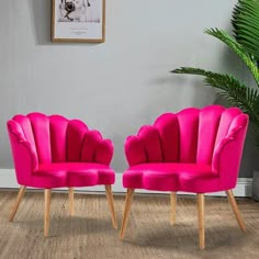 two pink chairs sitting next to each other in front of a potted green plant