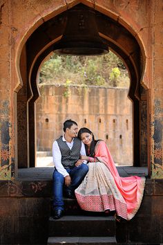 a man and woman sitting on a bench under an archway