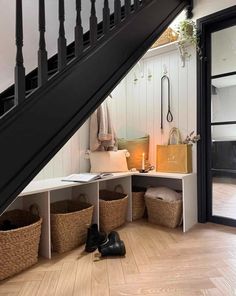 an entryway with baskets under the stairs