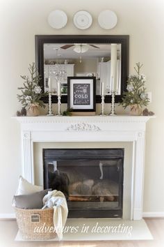 a fireplace with a mirror above it and some candles on top of the fire place