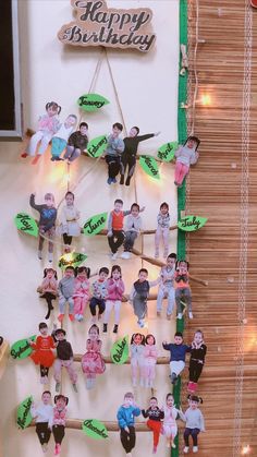 a group of children are hanging on the wall in front of a happy birthday sign