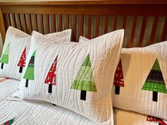 four pillows with christmas trees on them sitting on a bed