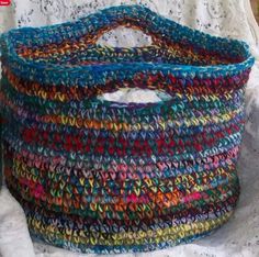 a multicolored basket sitting on top of a white tablecloth covered bed sheet