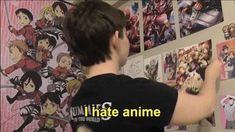 a boy is looking at anime pictures on the wall in front of him and pointing to them