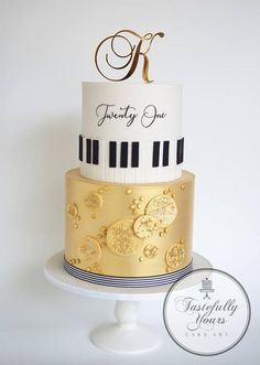 a three tiered cake decorated with gold and black piano keys