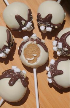 chocolate covered candy lollipops with marshmallow toppings on a wooden table