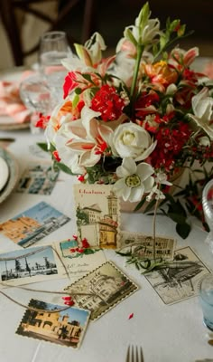 a table topped with lots of cards and flowers next to a vase filled with flowers