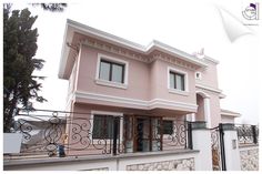 a pink two story house with wrought iron railings and balconies on the balcony