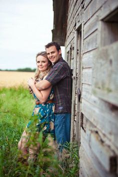 a man and woman standing next to each other in front of a barn