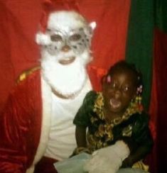 a child is sitting next to santa claus