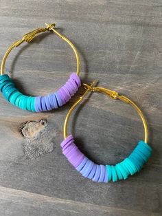 two pairs of hoop earrings with blue, purple and green beads on top of a wooden table